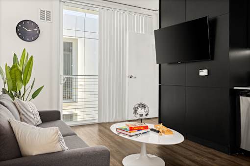 A living room with a grey couch, a white coffee table, and a black television.