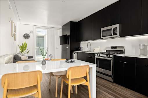 A modern kitchen with black cabinets and a white island.