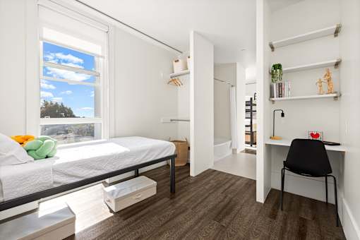 A bedroom with a bed, desk, and chair.