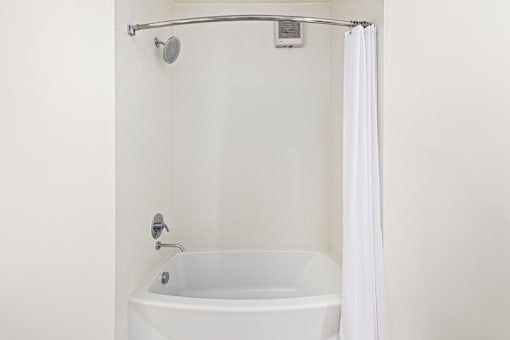 A white bathtub with a shower head and curtain.