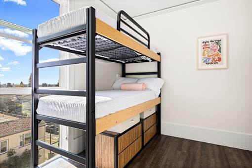A person is lying on a mattress on a bunk bed.