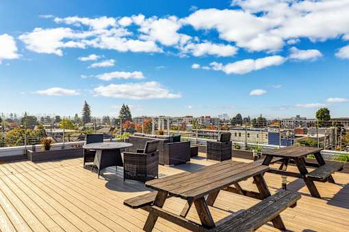 A wooden picnic table is in the foreground of a rooftop patio.