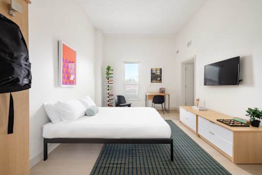 A bedroom with a bed, desk, and chair.