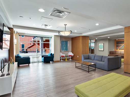 A spacious living room with a variety of seating options and a green ottoman.