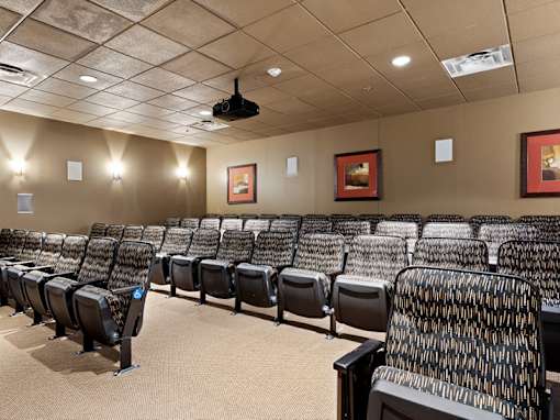 A row of black chairs with a projector screen above them.