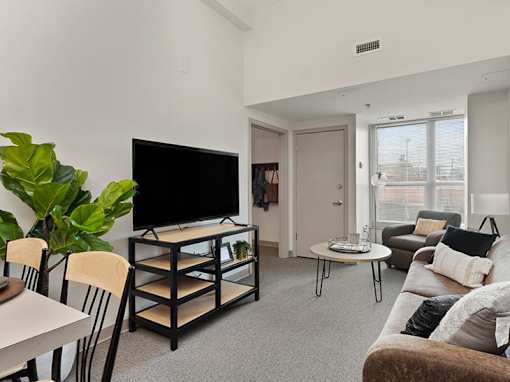 A living room with a television, a couch, and a dining table.