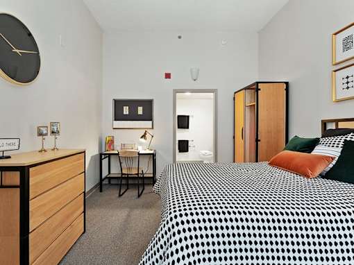 A bedroom with a bed, desk, and chair.