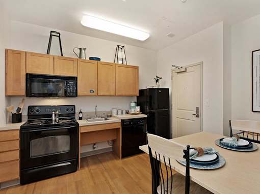 A kitchen with a black refrigerator, black oven, and black microwave.