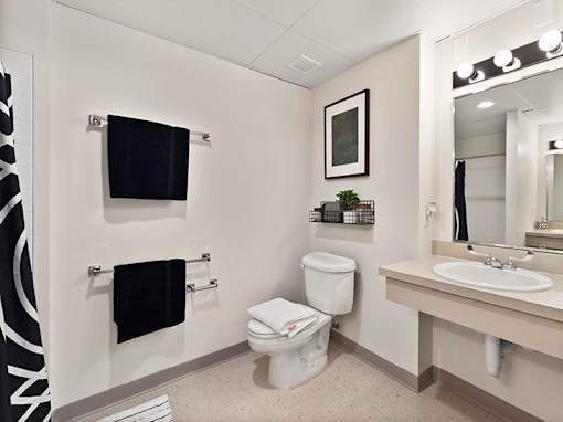 A white toilet sits in a bathroom next to a sink and a mirror.