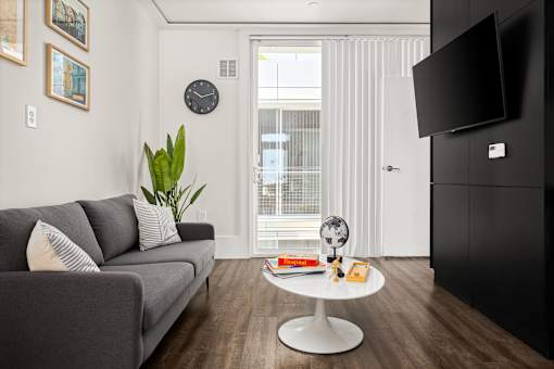 A living room with a grey couch, a white coffee table, and a black television.