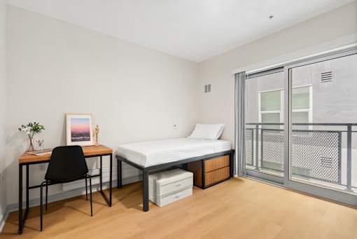 A bedroom with a bed, desk, and chair.