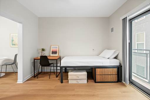 A bedroom with a bed, desk, and chair.