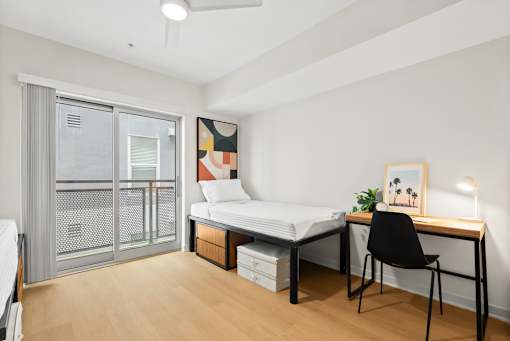 A room with a bed, desk, and chair.