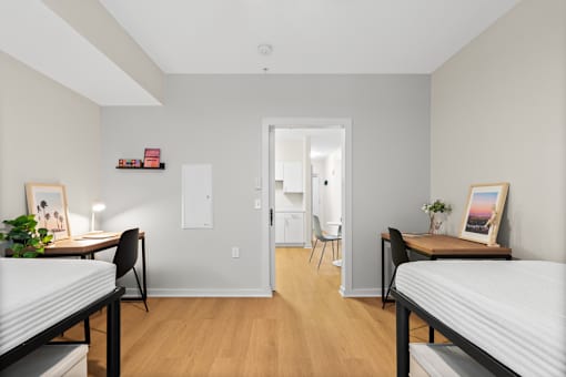 A room with two single beds and a desk with a chair.
