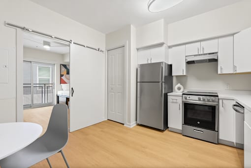 A kitchen with a white table and a white chair.