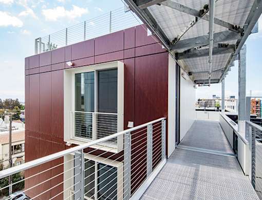 A red building with a white railing and a metal roof.