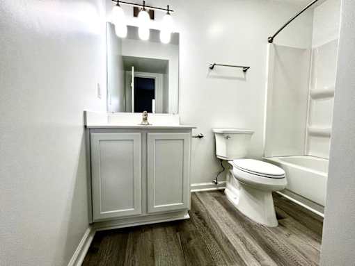 A white bathroom with a toilet, sink, and mirror.