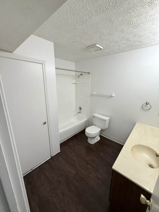 Waterford Court SN1 bathroom. A white toilet sits in a small bathroom with a sink and a shower.
