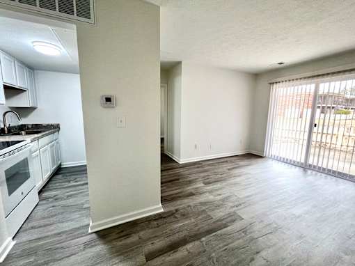 A kitchen with white appliances and a wooden floor.
