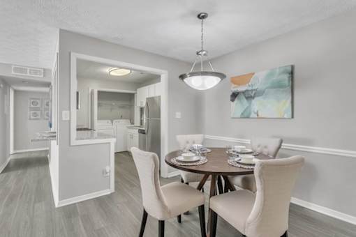 A dining room with a table set for two and a painting on the wall.