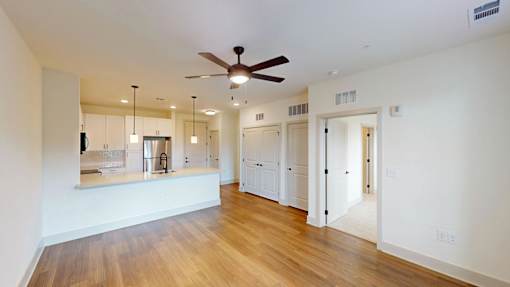 A spacious room with a ceiling fan and wooden floors.