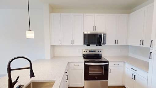 A kitchen with white cabinets and a black stove top oven.