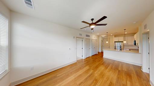 A room with a ceiling fan and wooden floors.