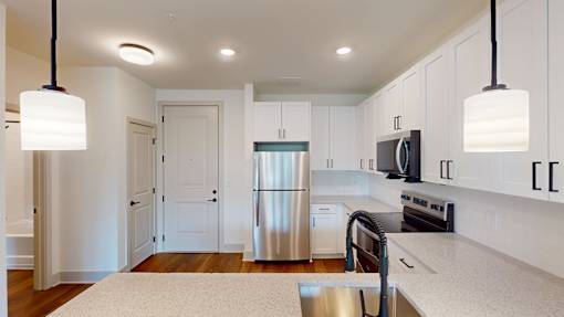 A modern kitchen with a stainless steel refrigerator and white cabinets.