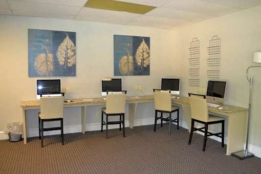 a computer room with four desks with computers and chairs