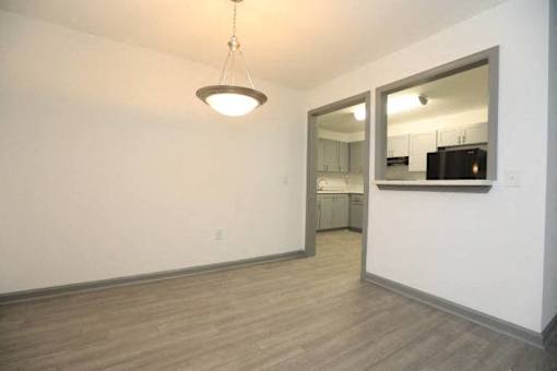 an empty living room with a mirror and a white wall