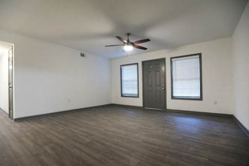 an empty living room with a ceiling fan and a door