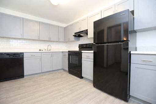 an empty kitchen with black appliances and white cabinets