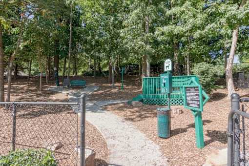 A green sign with a white arrow pointing to the right is on a post in a park.