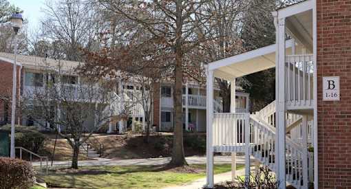 the front porch of an apartment building with a tree in front of it