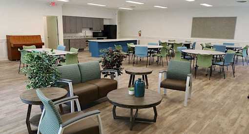a large room with tables and chairs and a kitchen