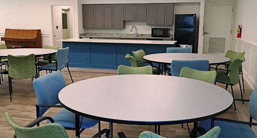 a dining room with tables and chairs and a kitchen with a sink