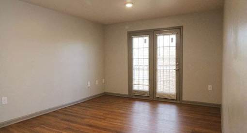 an empty living room with a hard wood floor and doors