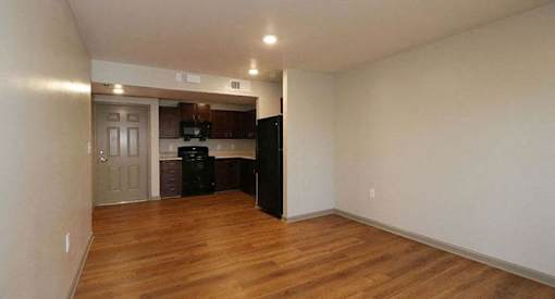an empty living room and kitchen with a wood floor