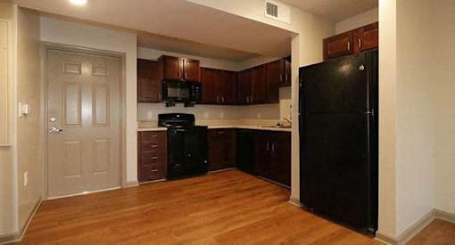 a kitchen with black appliances and wooden floors