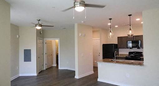 a living room with a kitchen and a ceiling fan