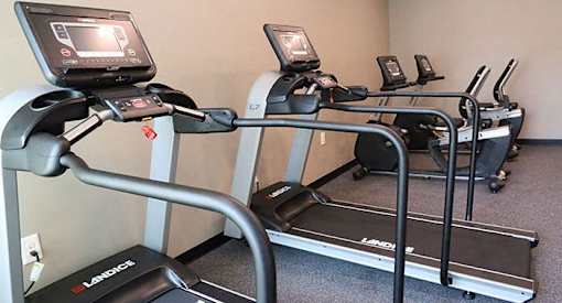 two treadmills in a gym with a screen on top of them