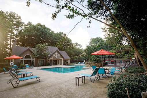 a swimming pool with chairs and umbrellas in front of a house decatur luxury living