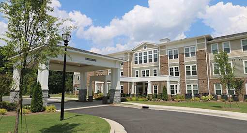 an exterior view of a large building with a driveway and trees
