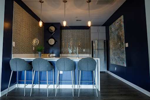 a kitchen with blue chairs in front of a bar with a sink