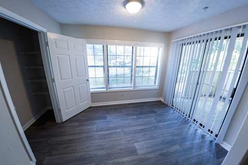 an empty living room with a large window and a closet