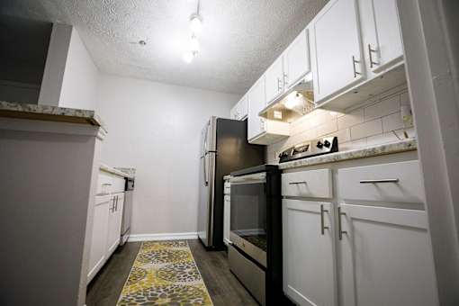 a kitchen with white cabinets and a black stove and refrigerator