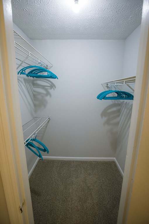 a walk in closet with two hanging shelves and a white wall