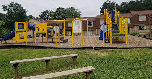 A playground with a yellow and blue slide, a yellow and blue climbing frame, and a yellow and blue swing set.