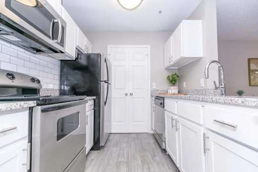 A kitchen with white cabinets and a black fridge.