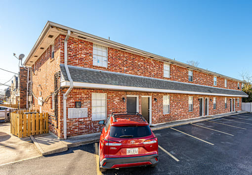 A red car is parked in front of a brick building.